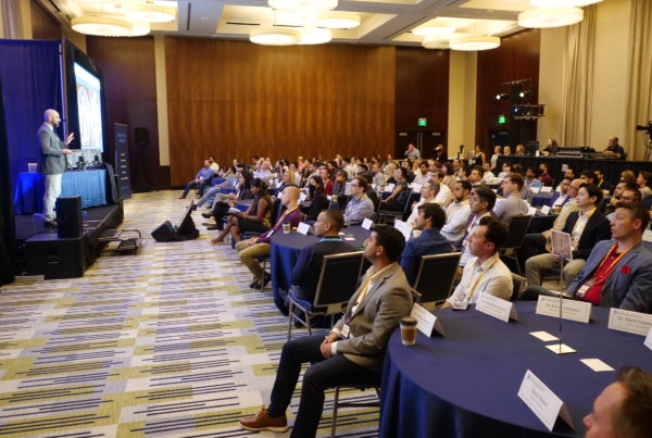 Speaker on stage presenting to large group