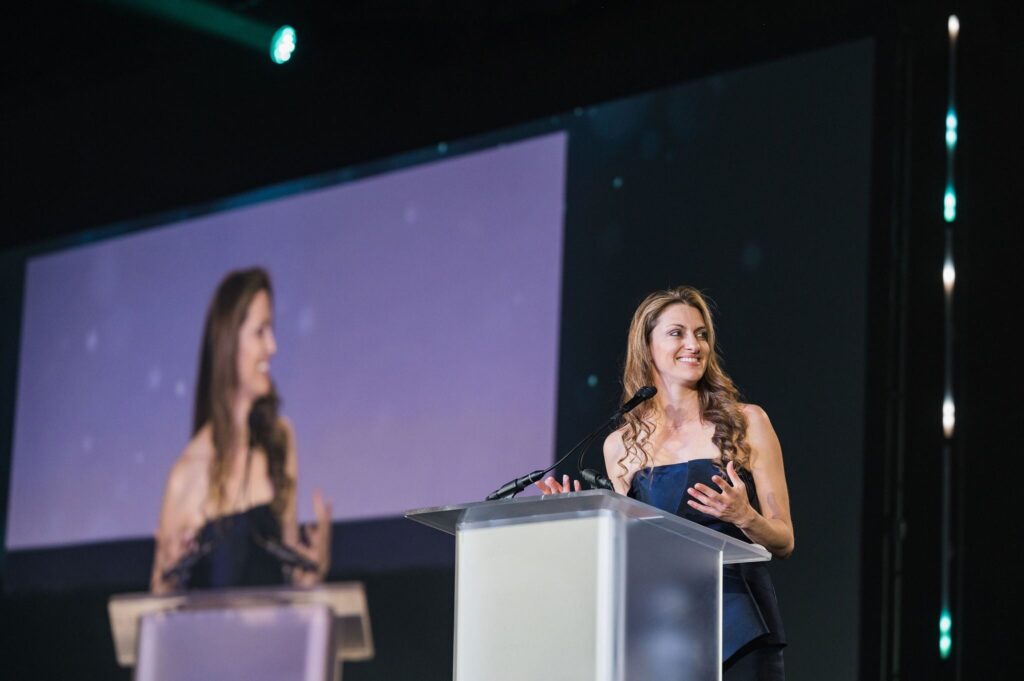 woman stands at a podium smiling