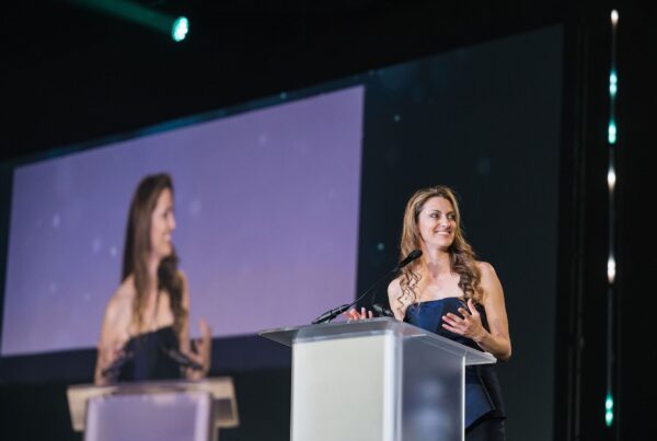 woman stands at a podium smiling