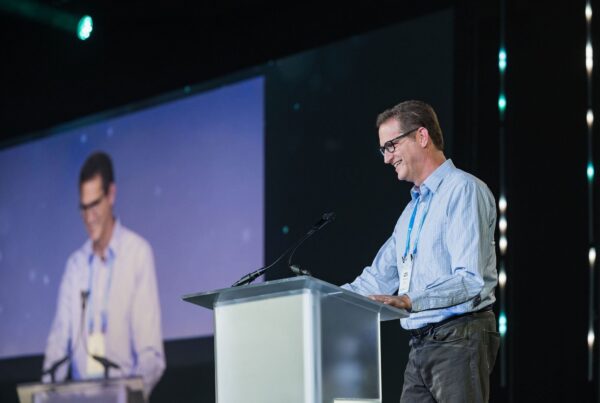 man stands at a podium smiling