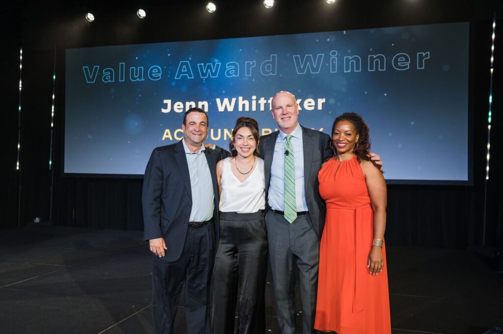 two women and two men stand on stage smiling