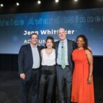 two women and two men stand on stage smiling