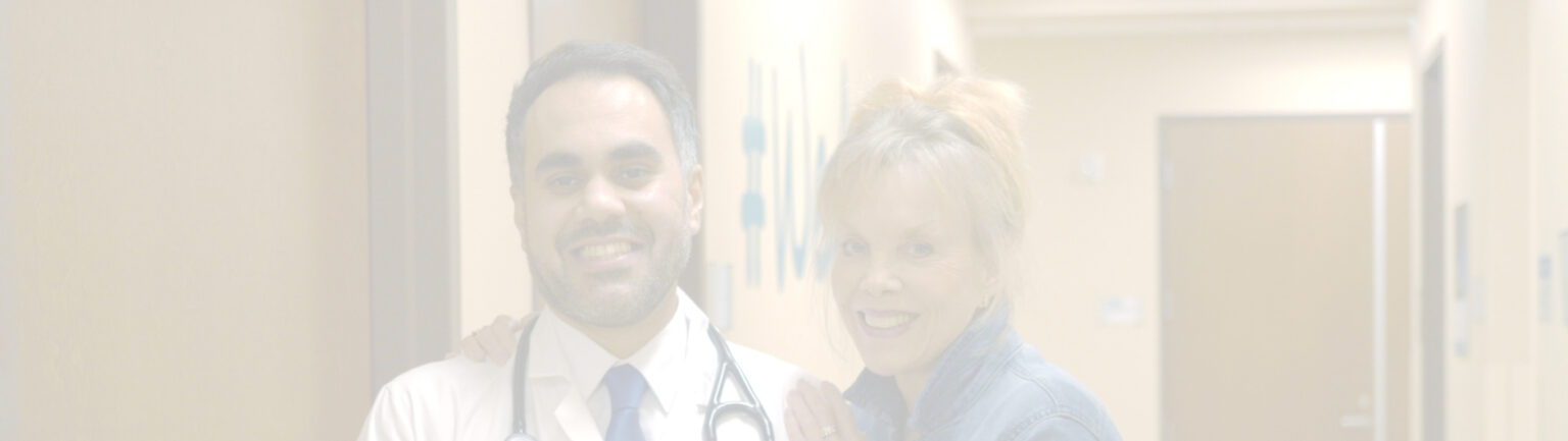 A doctor with a stethoscope around his neck stands next to a smiling woman in an RP clinic hallway, both looking at the camera. The image is faded and softly lit.