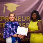 two women exchanging a handshake and an award.