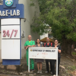 4 people posing behind a department of radiology sign